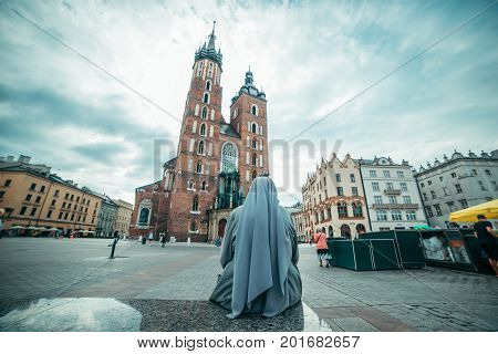 nun looking on old church in dramatic weather