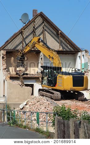 demolition of an old house with a chain excavator half done