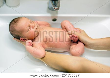 Sweet Newborn Boy, Having His Bath In Mothers Hands