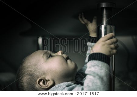 little boy stands and holds onto the table to not fall and extends up