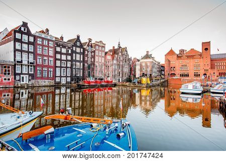 Morning view on the beautiful buildings and boats on the Damrak avenue in Amsterdam