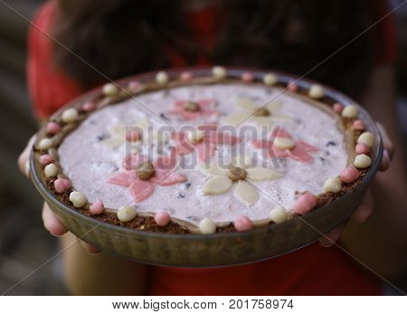 oat cacke with jogurt topping and marzipan flowers on the top hand hold