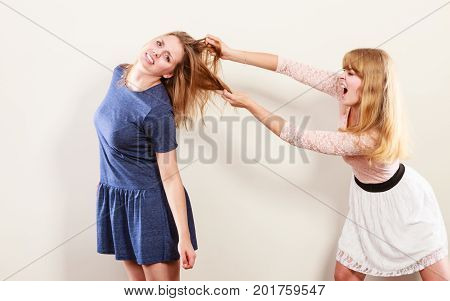 Aggressive mad women fighting each other pulling hair. Two young girls struggling win catfight. Violence.