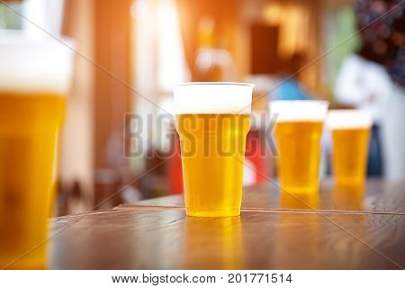 A row of plastic beer glasses with a light beer on a party