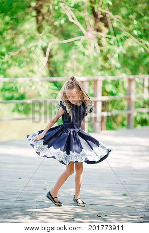 Adorable little school girl with notes and pencils outdoor.