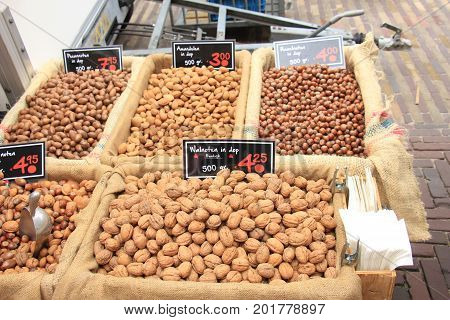 Fresh unpealed nuts on a market stall (text on tags: names and prices of various nuts in Dutch walnuts Pecan almonds and hazel)