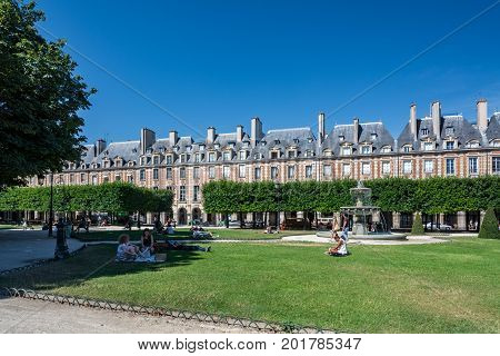 Paris France - August 13 2016: Tourists on the Place des Vosges originally Place Royale is the oldest planned square in Paris and one of the finest in the city.