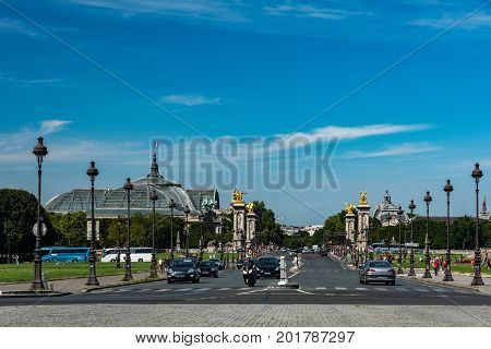 Paris France - August 14 2016: Cars and tourists on the Alexandre III bridge known for its golden statues with view of the big palace in the background.