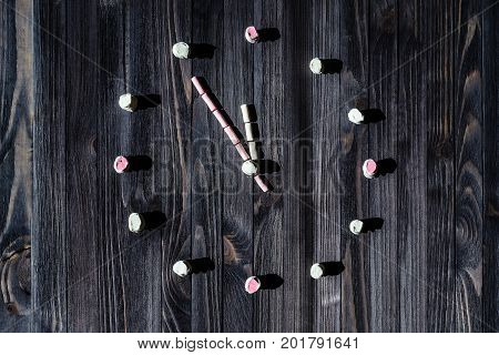 A dial of watches from white and pink marshmallows on a black wooden board background.