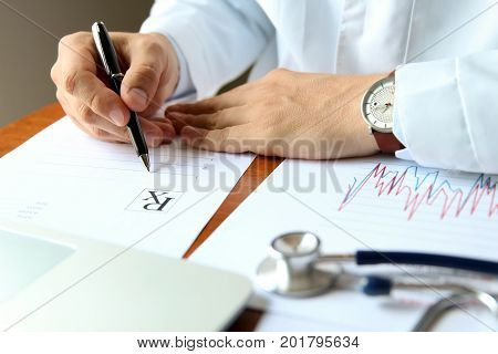 doctor working on a computer at his cabinet / writing prescripton