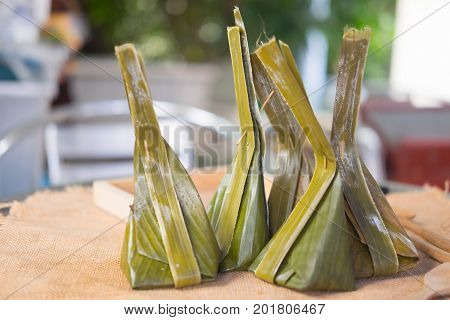 Thai dessert made from steamed flour with filling inside wrapped with banana leaf it called 