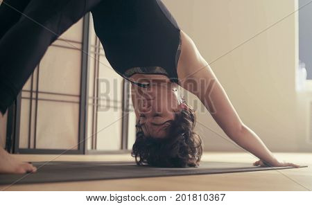 A young woman performing yoga-asanas in the hall. Artha mukha svanasana.