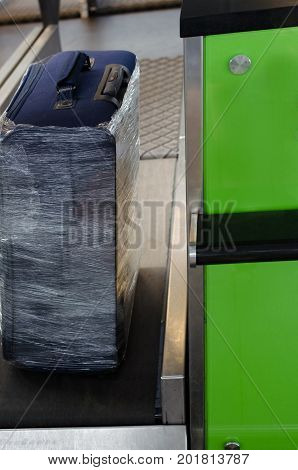 Checking the weight of luggage in the airport during the check-in by low cost airlines restrictions. Wrapping baggage before travel by airplane. Suitcase in protective transparent film.
