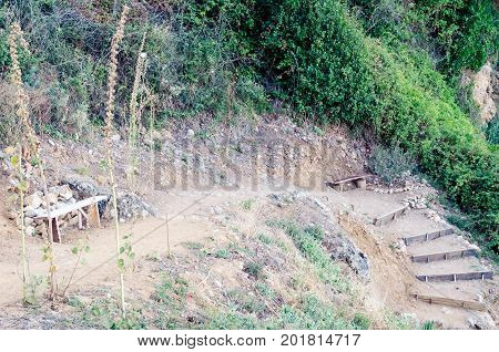 Ground stair step walkway with a wooden bench. Wooden steps in the ground. Stairs in the cliffs to the beach Liman in Ulcinj Montenegro.