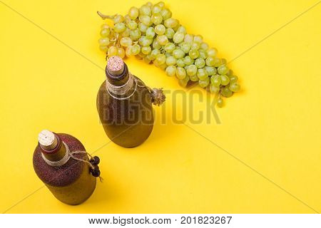 bottle of white wine with grapes on a yellowbackground