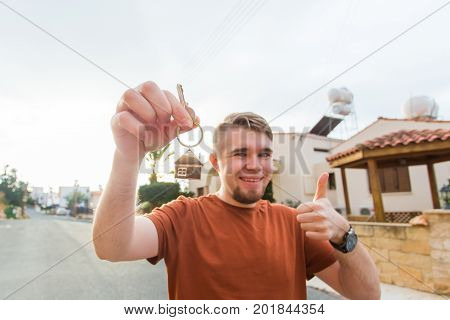 Happy young man showing off the key to his new home. Owner, real estate and people concept.