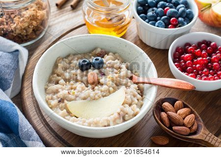 Meal for kids - oatmeal porridge bowl with cute funny face made with fruits. Cozy breakfast food