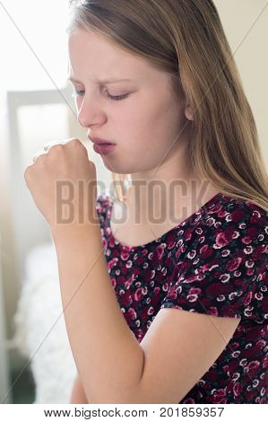 Girl Suffering With Cough Sits On Bed At Home
