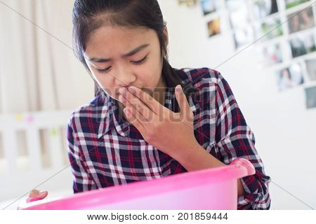 Young Girl Sitting On Bed At Home Feeling Nauseous