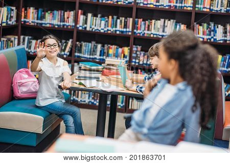 beautiful multiethnic schoolgirls greeting at school library