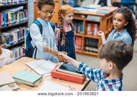 little pupils shaking hands in school library