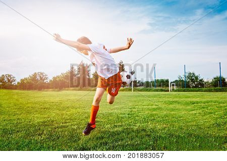 Boy Playing With Football Ball On Playing Field.