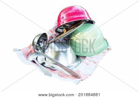 Kitchen utensils on a towel on white background. On the towel are plates, a ladle and spoons
