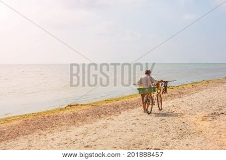 Seller of fish sells fish on the beach by bike.