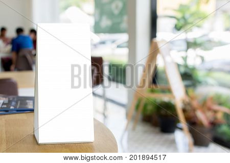 Mock up blank template menu frame on wood table in restaurant with blurred background Clipping path included