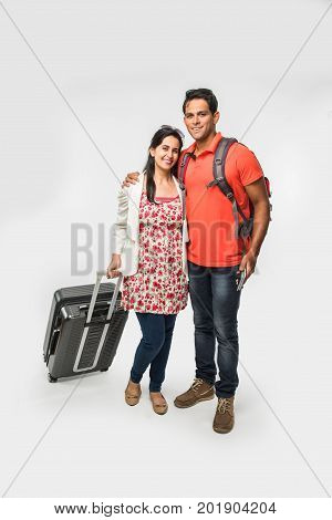 stock photo of smart Asian or Indian couple traveler with suitcase and hike bag isolated over white background, going abroad or within country, perfect shot for tours and travels company