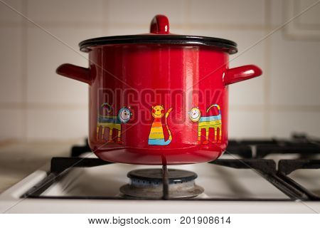 Red saucepan on the gas stove. Kitchen pot on the gas stove.