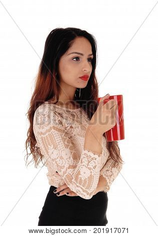 A gorgeous young business woman in a beige blouse and black skirt holding a red big coffee mug looking serious over white background