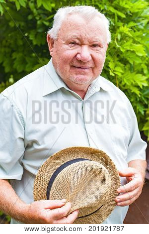 Portrait of a happy caucasian old man smiling at the camera in the garden