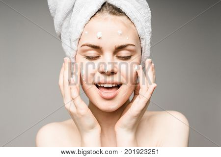 Beauty Woman face Portrait. Beautiful model Girl with Perfect Fresh Clean Skin.towel on the head.Youth and Skin Care Concept. Isolated on a white background.Woman applying a cream to face.
