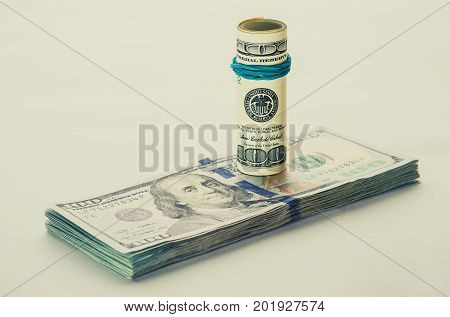 A coiled 100 dollar bill which rests on another angled 100 dollar bill isolated on white background. American bank notes isolated on the white background