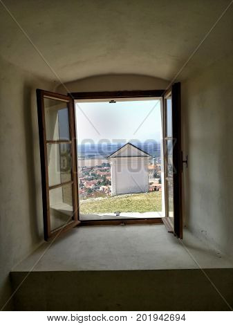 Artistic view from the window to the chapel and town. A patch of sky and grass on a hill,