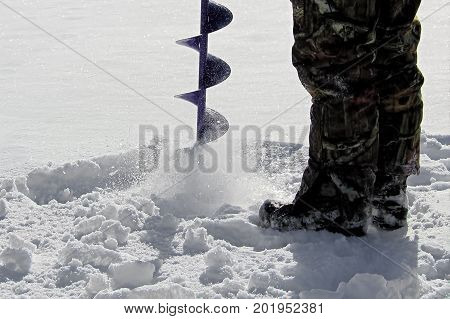 Side View Of Drilling A Hole For Ice Fishing