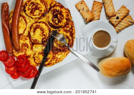 Breakfast of an omelette with sausages and coffee on a white wooden background