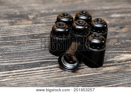 Set of plastic and ceramic electric cartriges for bulb on black wooden background.
