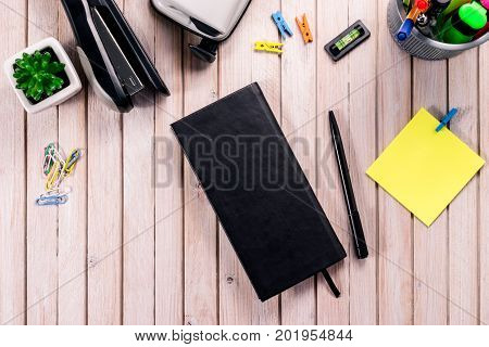 Top view workspace mockup on wooden background with blank notebook with copy space, pen, tacker, punch, clips and accessories. Overhead view. Flat lay, top view