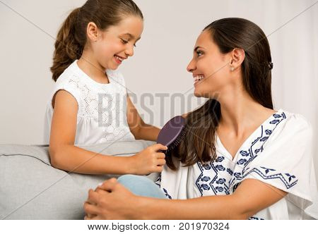 Litle girl helping mother brushing her hair