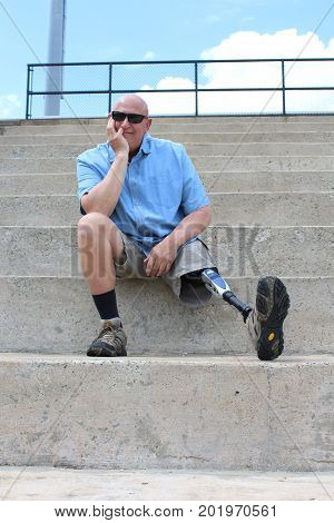 Seated amputee man with prosthetic leg extended