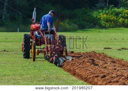 DUNDAS, PRINCE EDWARD ISLAND, CANADA - 25 Aug: Competitor plows with antique tractor at the PEI Plowing Match and Agricultural fair on August 25, 2017 in Dundas, Prince Edward Island.