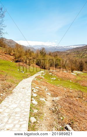 Landscape with snowy mountains and valley on blue cloudy sky background in Okatse canyon. Georgia Caucasus. Multicolored summertime outdoors vertical image.