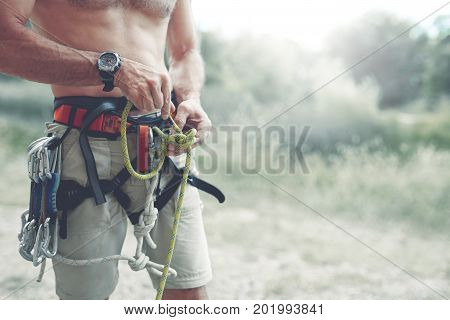 A man climber Knots a knot on a climbing harness. hands in chalk close up