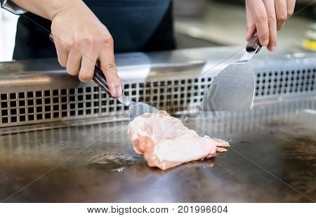 Hand Of Chef Cooking Chicken Steak On Hot Pan In Front Of Customers.