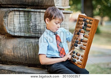 Boy With Large Abacus. Thoughtful Schoolboy Using A Maths Abacus Calculation. Farewell Bell. Day Of
