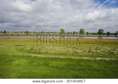 Beautiful View On A Typical Dutch Landscape Near The River Waal And Water, Green Grass, Meadows And