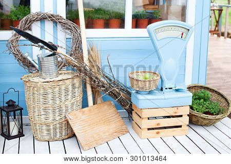 Wicker Baskets Next To The Garden Equipment Against The Wall Of A Blue Country House. Summer Seasona