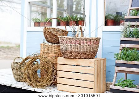 Wicker Baskets Next To The Garden Equipment Against The Wall Of A Blue Country House. Summer Seasona